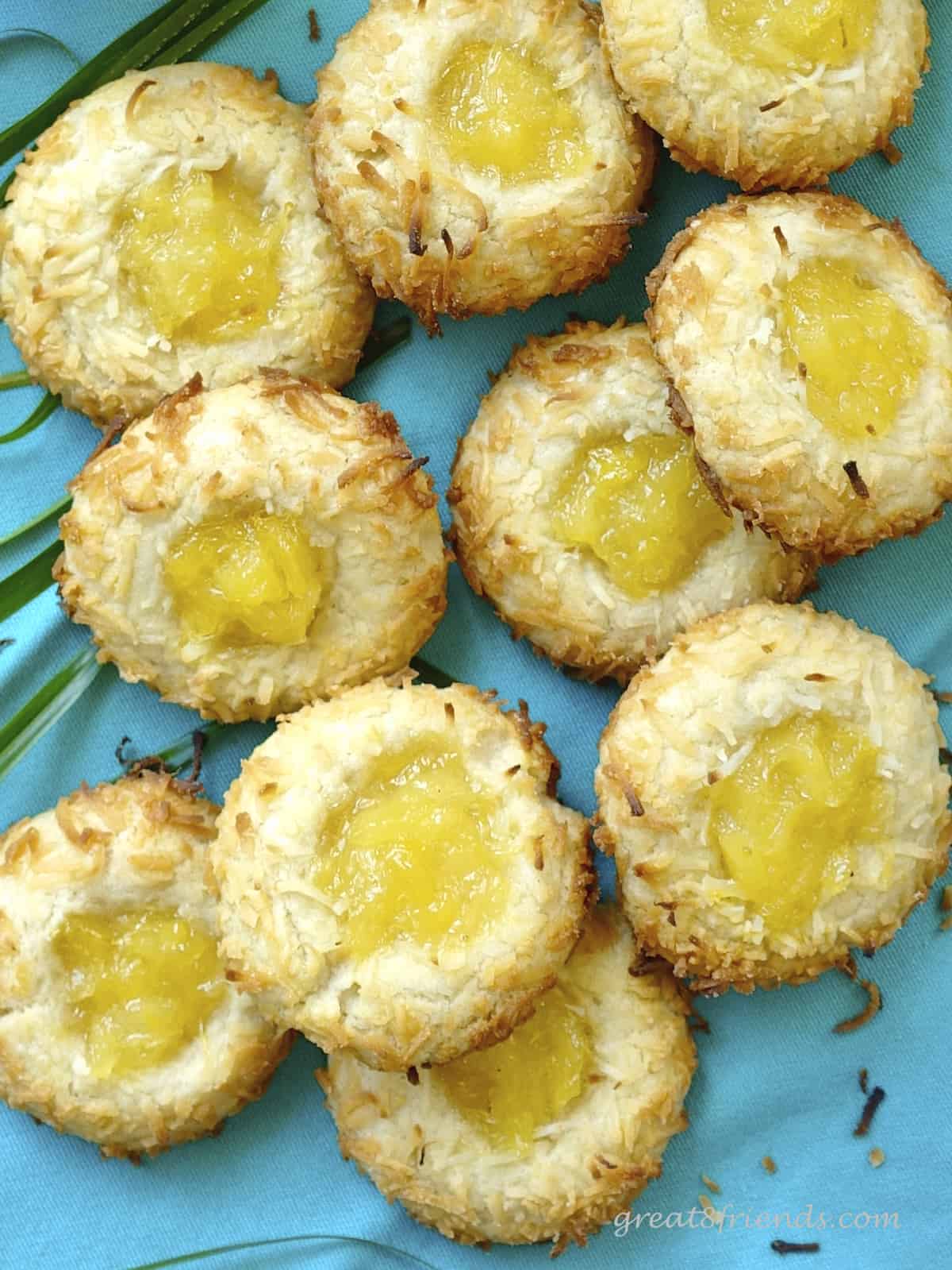 Over head close up shot of coconut pineapple thumbprint cookies on a blue background.