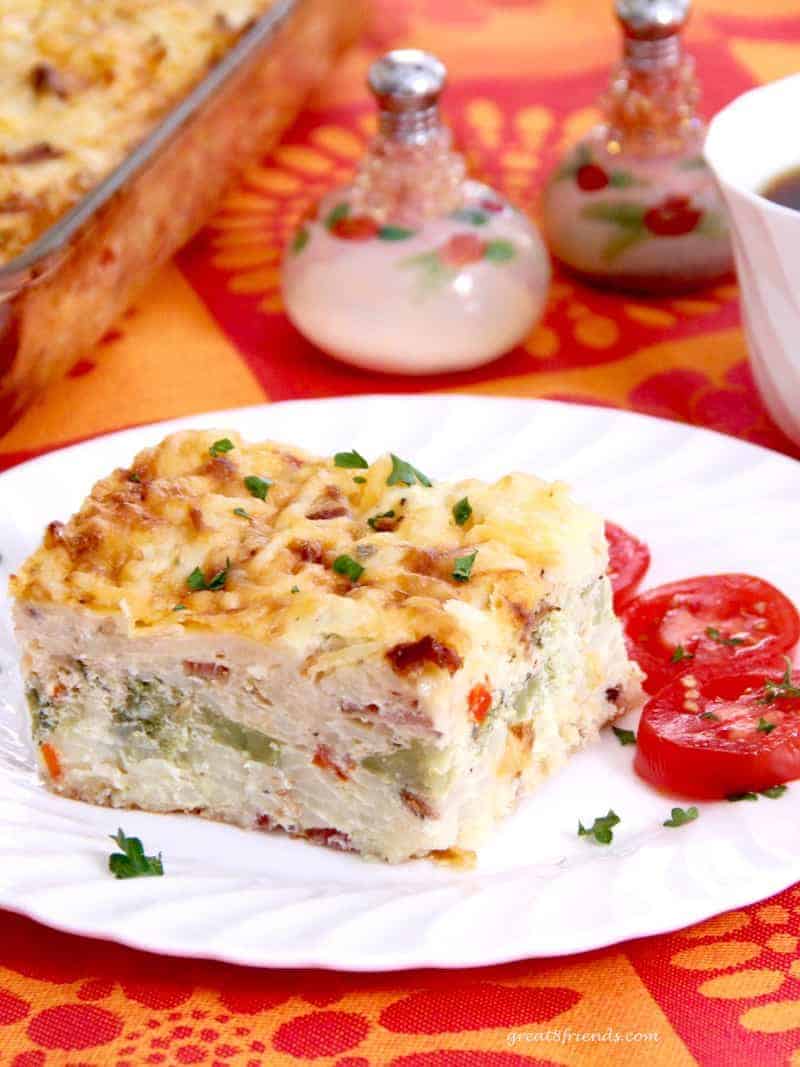 Hash brown egg casserole served on a plate with sliced tomatoes.