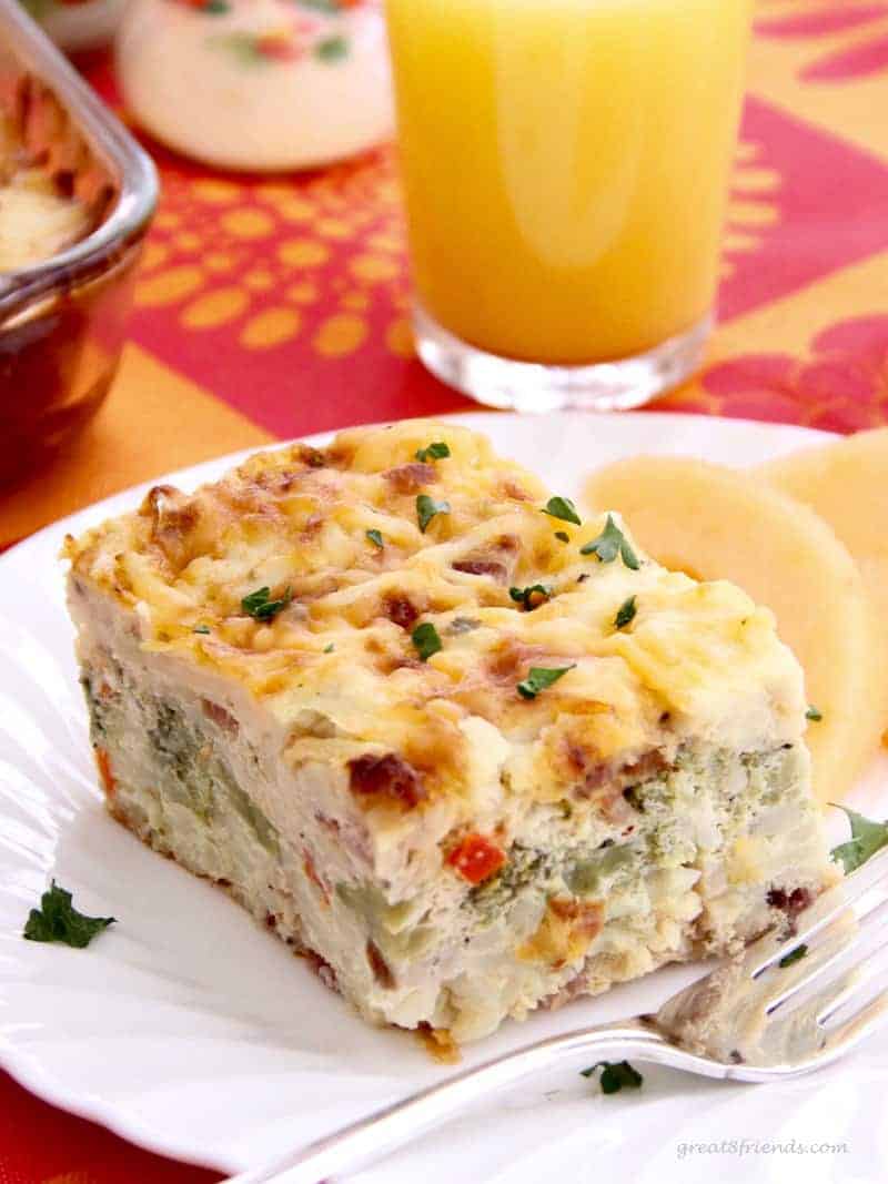 Hash brown egg casserole served with sliced cantaloupe and orange juice.