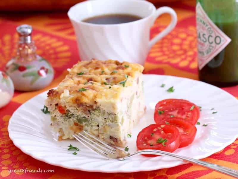 Hash brown egg casserole served with sliced tomatoes and a cup of coffee.