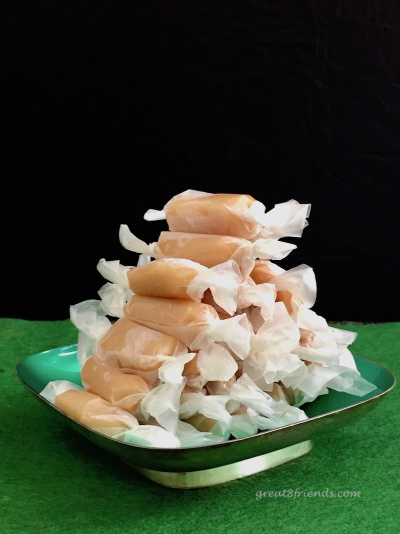 Creamy Caramel candy stacked in pyramid shape on green dish on green felt.