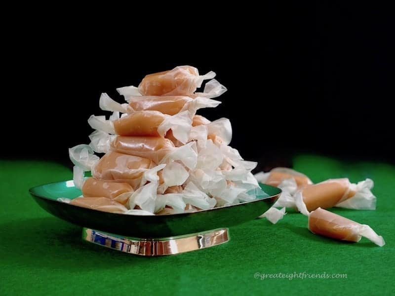 Creamy Caramels stacked in pyramid shaped on green dish on green felt with 3 loose caramels.