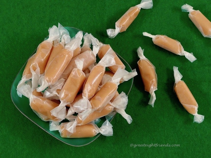 Caramels wrapped in waxed paper on a green felt background.