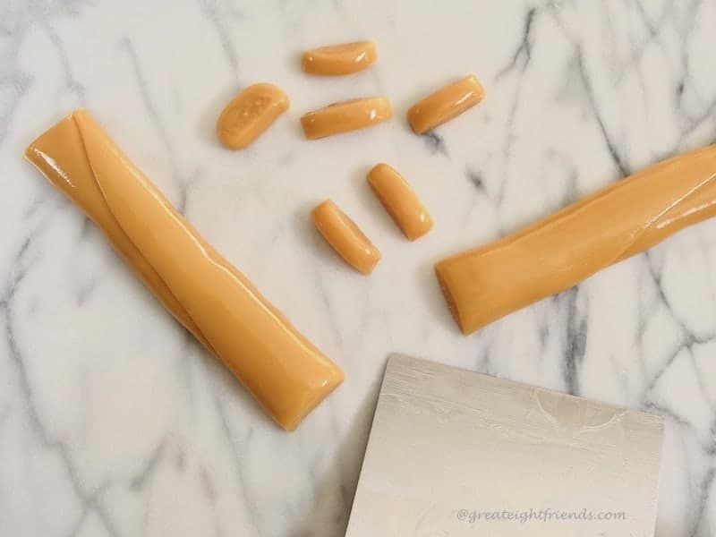 Creamy Caramels being cut before wrapping.