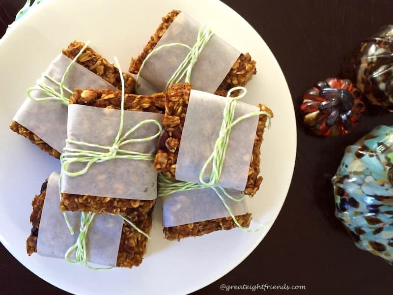 Pumpkin Granola Bars wrapped in parchment, tied with green twine and stacked on a plate.