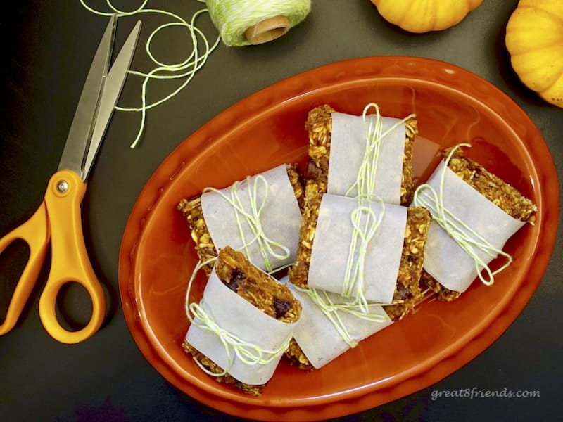 Pumpkin Granola Bars wrapped in parchment and stacked on an orange plate.