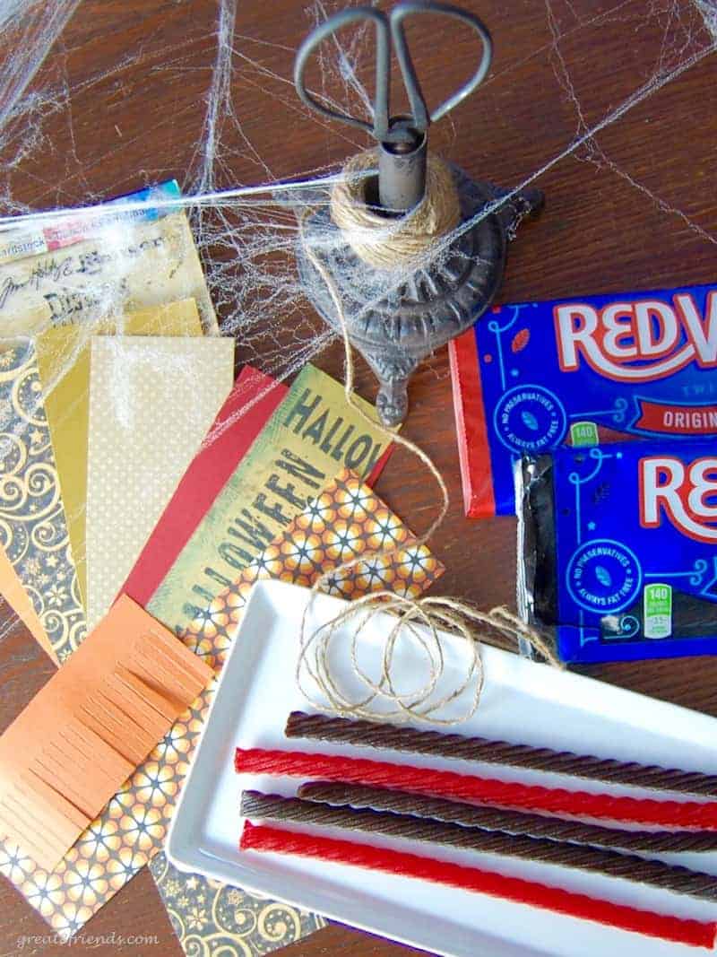 A tabletop covered with scrap paper pieces and red vines.