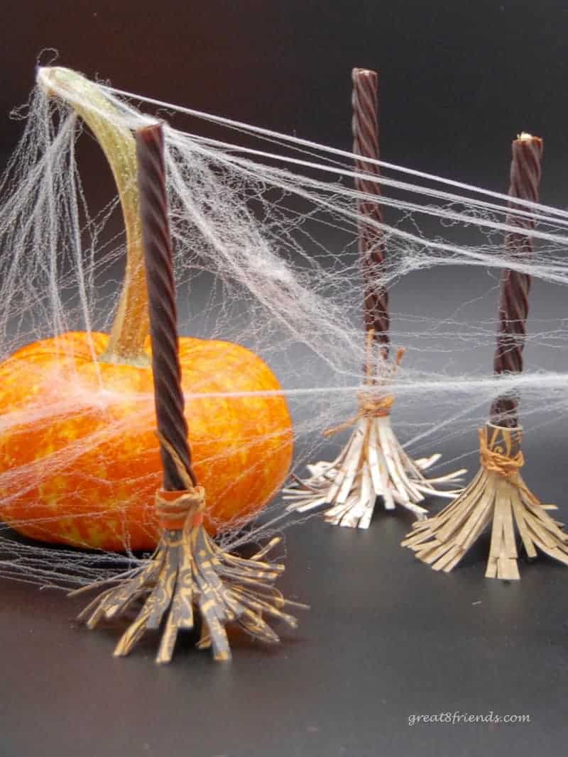 Three Witch's Brooms and one mini pumpkin with fake spider web all over.