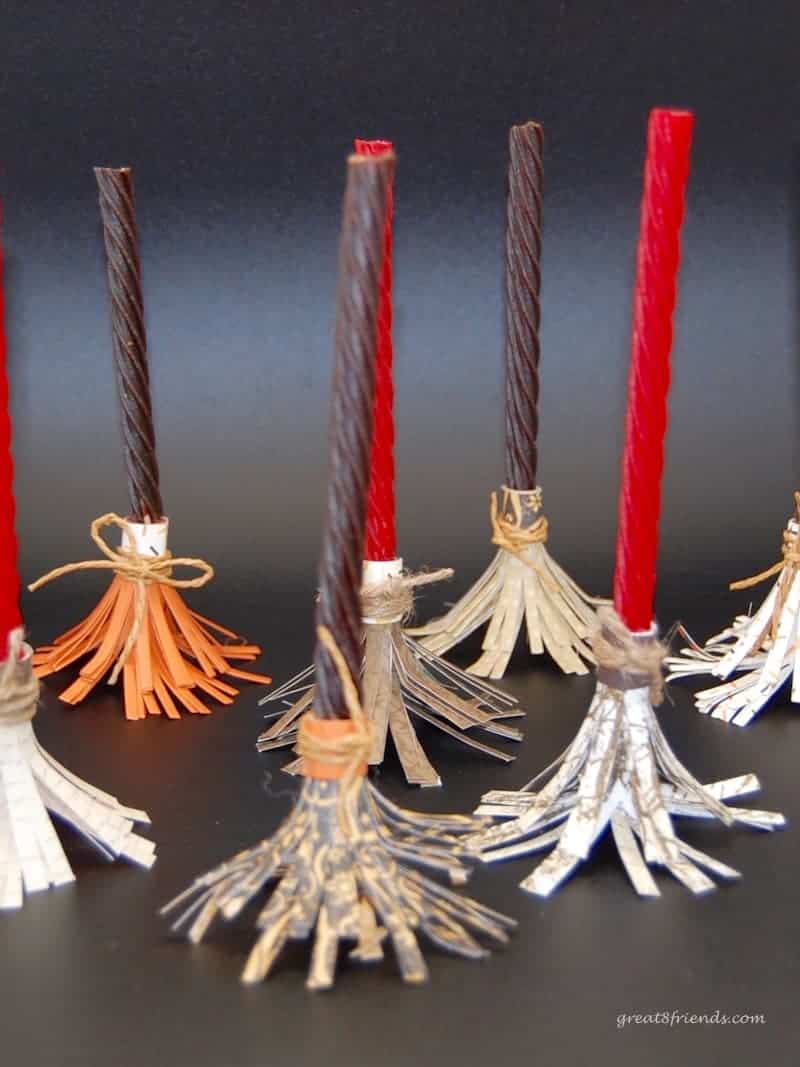 Several of the witch's brooms made from candy vines and paper standing up.