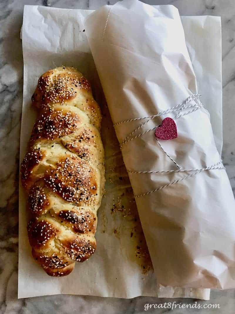 Overhead shot of 2 loaves of challah bread. One wrapped in parchment. 