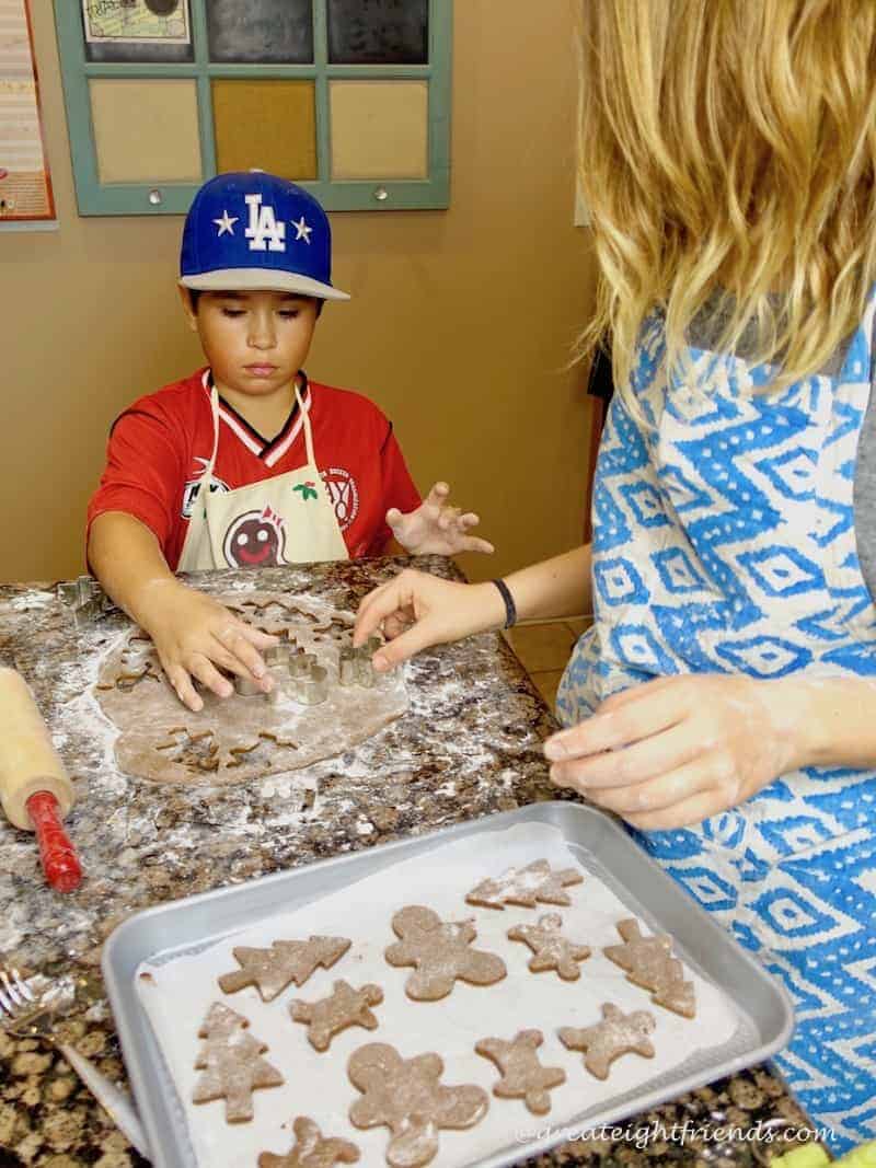 A young woman and girl cutting out cookie dough for Christmas cookie bake.