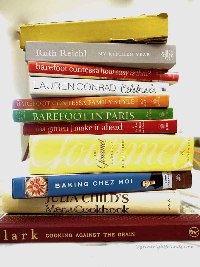 A stack of cookbooks, some old and worn, some newer.