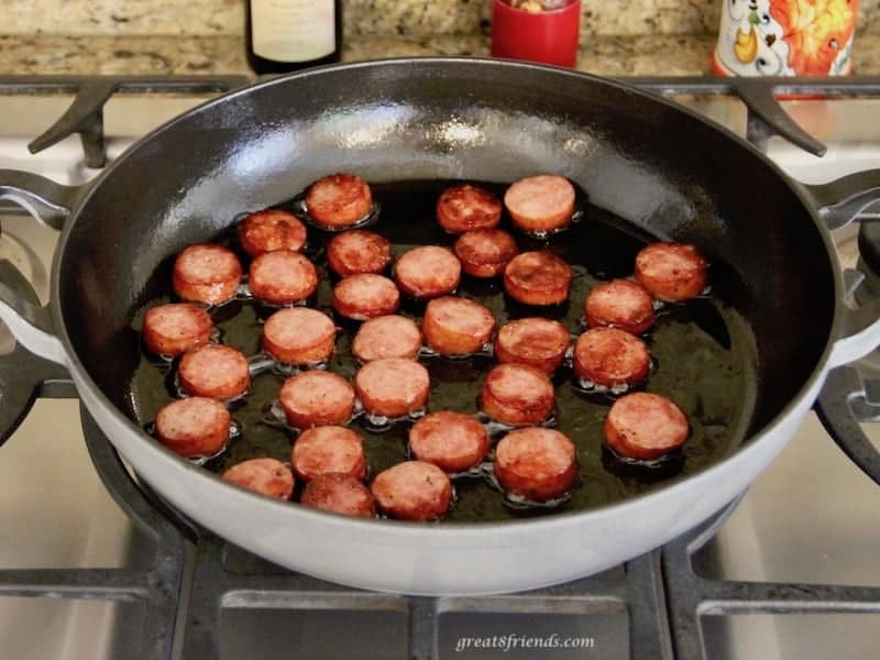 slices of sausage sautéing in a pan.