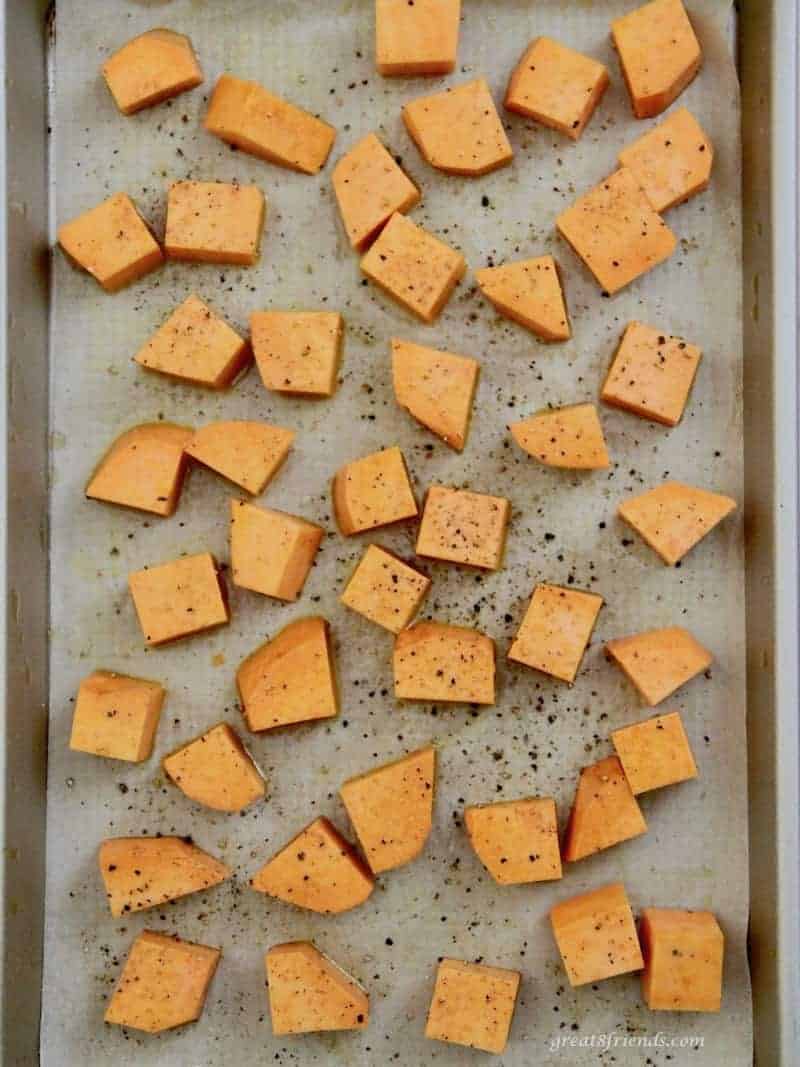 one inch squares of sweet potato sprinkled with pepper on a baking sheet.