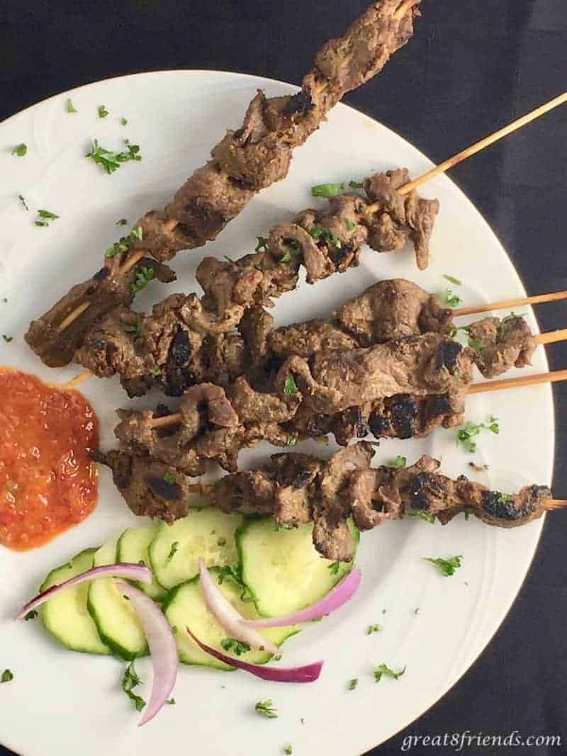 beef satay skewers with sauce and cucumbers