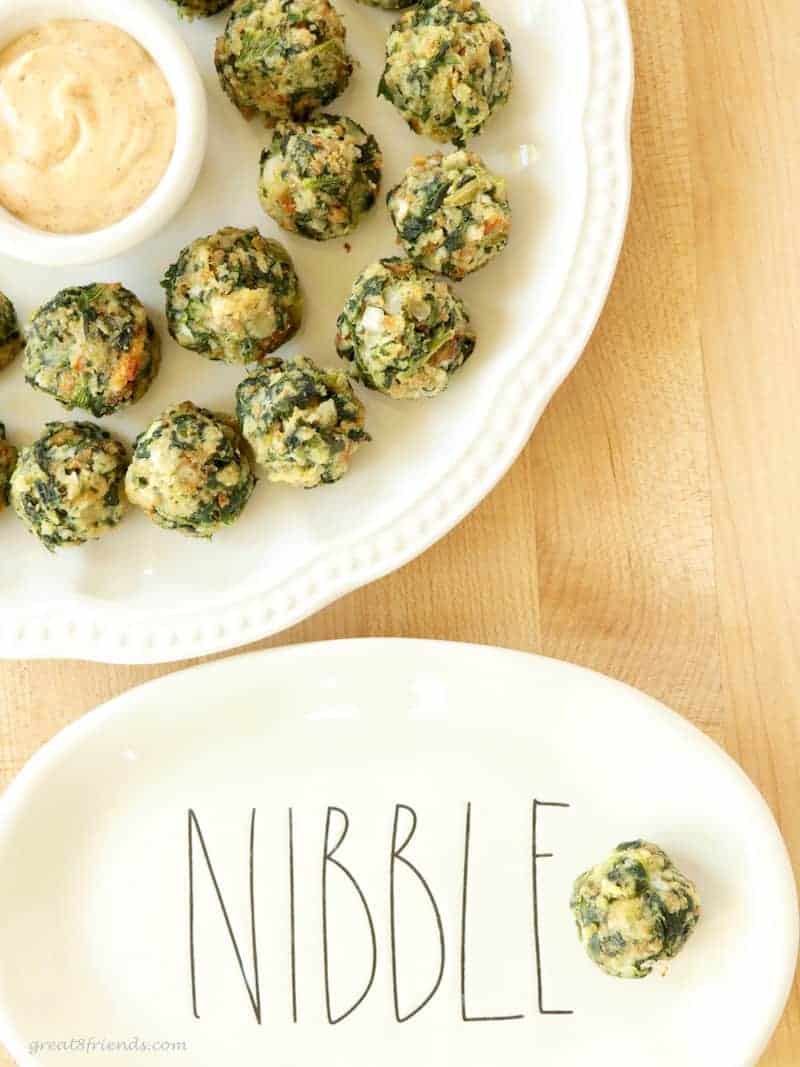 Small spinach with stuffing appetizers served on a plate that says "nibble."