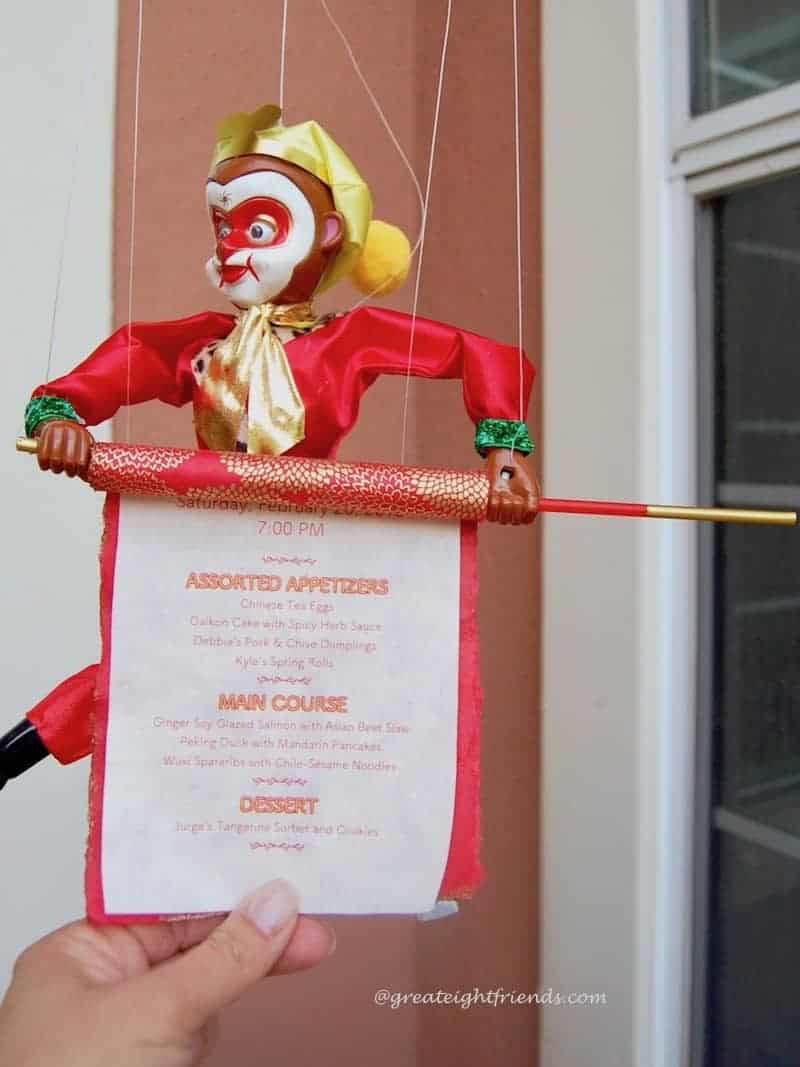 Chinese new year monkey marionette holding a scroll invitation.