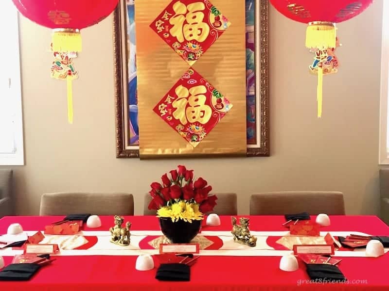 Table set for Chinese new year with paper lanterns hanging above.