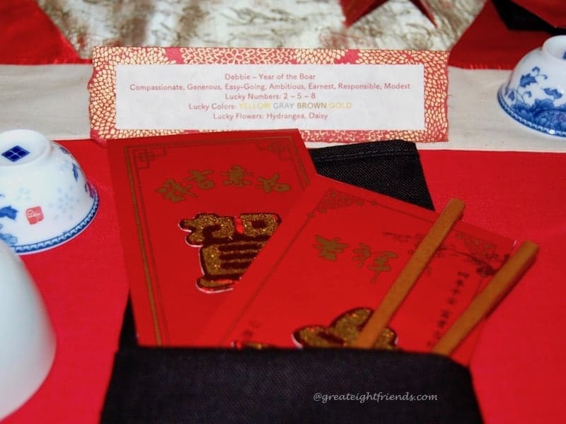 Chinese New Year place setting with red money envelopes and chopsticks.