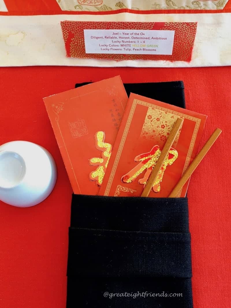  Lunar New Year place setting, a folded black napkin with red money envelopes and chopsticks.