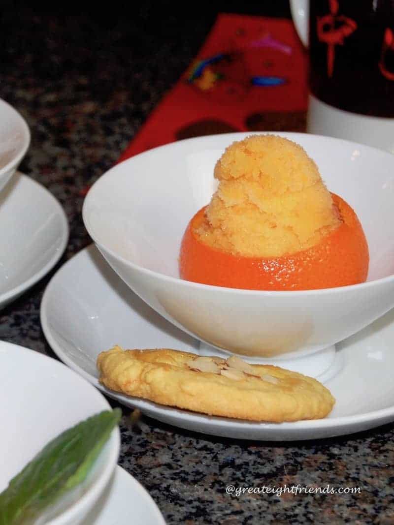 Tangerine sorbet in a white bowl with an almond cookie.