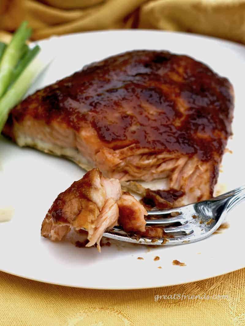 Glazed salmon on a white plate with a forkful of a piece of salmon.