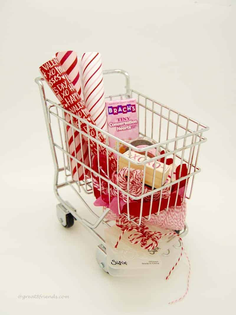 Valentine's paper and candy and string in a mini shopping cart.