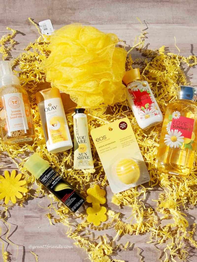 Yellow loofah, and various yellow body products laying on yellow shred.