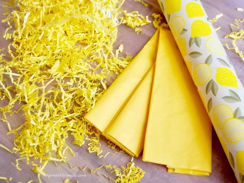 Yellow shred, yellow tissue and a roll of wrapping paper with lemons on it.