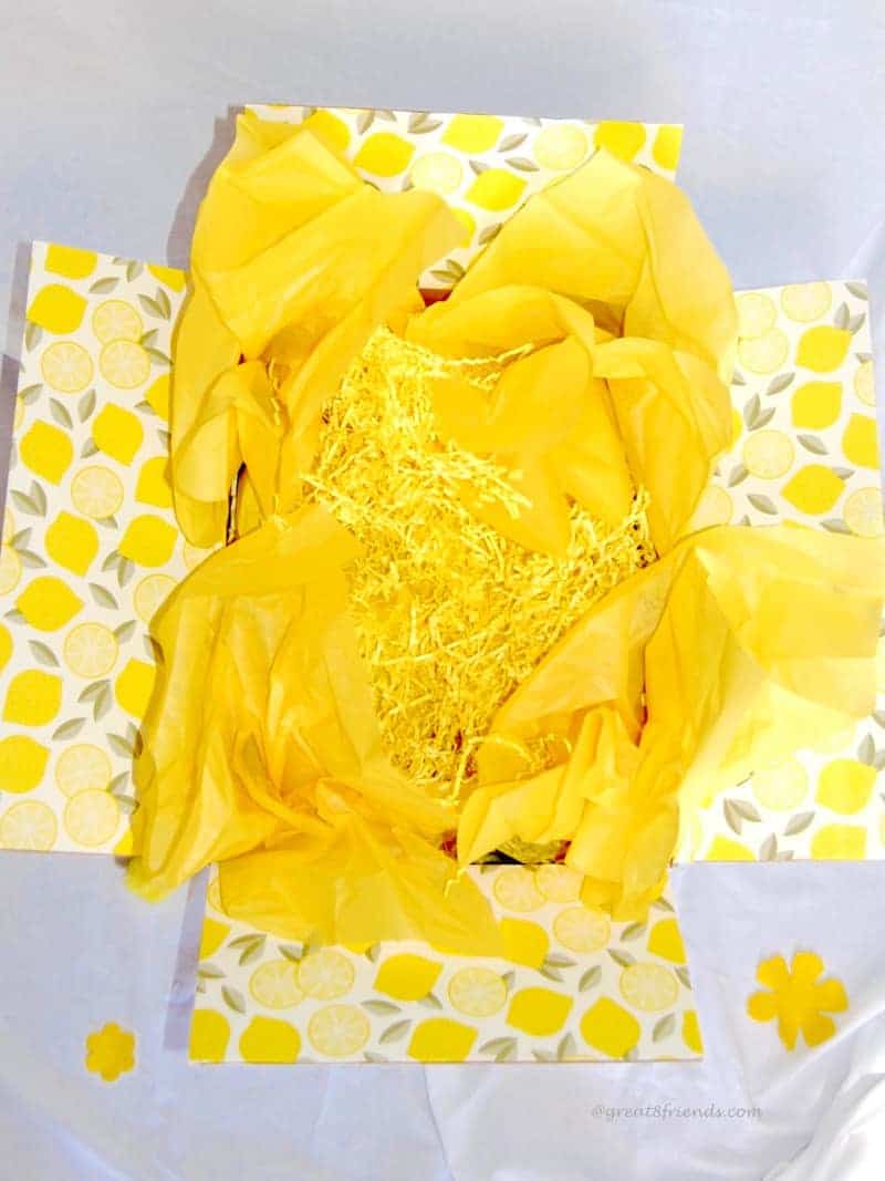 A yellow box filled with yellow tissue paper and yellow shred.