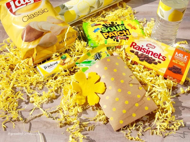 Yellow packaged snacks laying on yellow shred.