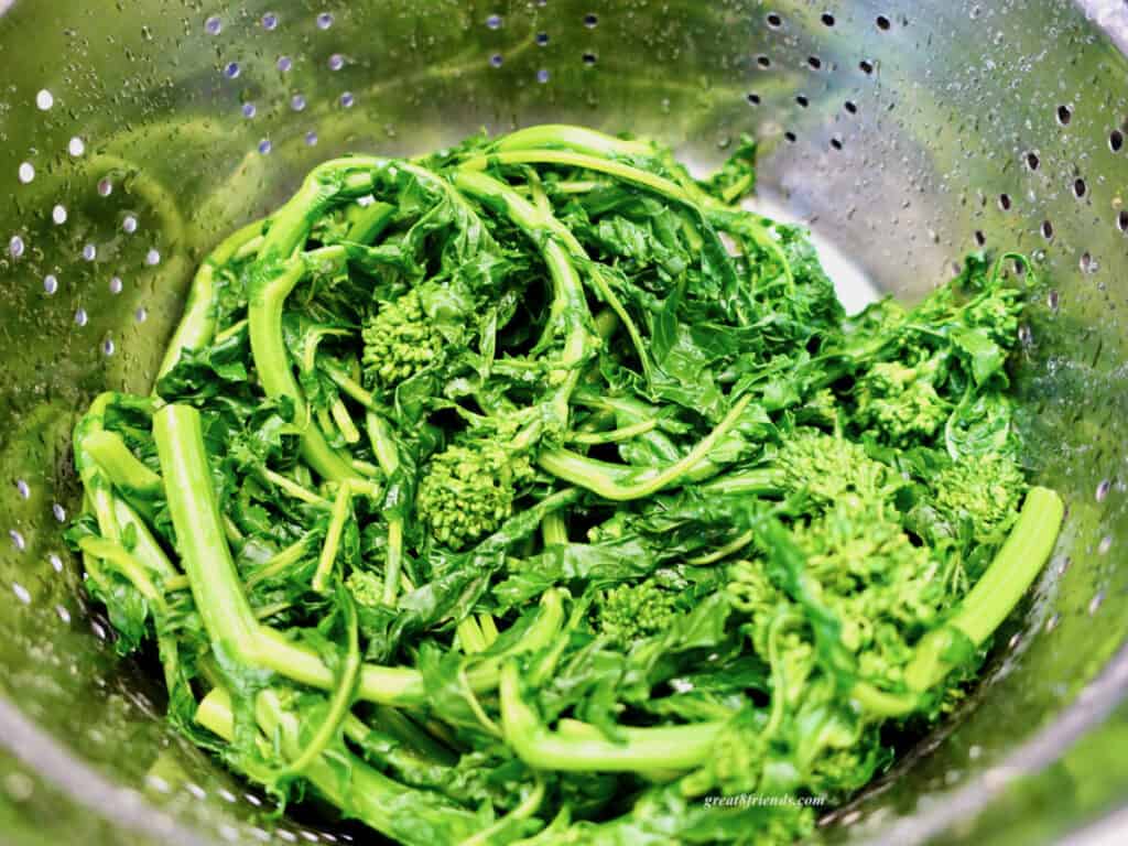 Overhead shot of broccoli rabe after par boiling in a colander.