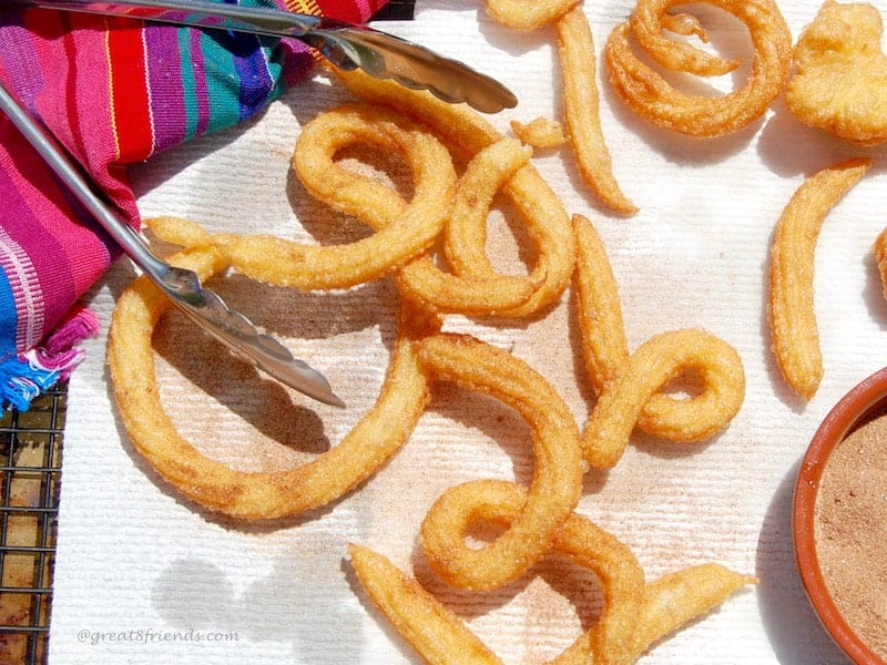 Overhead shot of curly churros draining on paper towels.