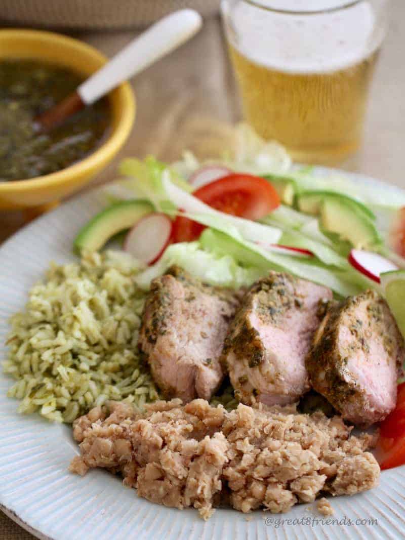 Adobo Marinated Pork Tenderloin sliced with refried beans, rice and a green salad.
