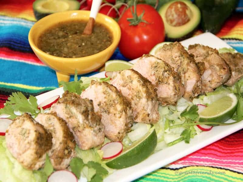 Adobo Marinated Pork Tenderloin sliced on a platter with lime slices.