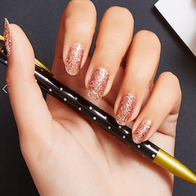 Manicured glitter fingernails on a hand holding a pen.