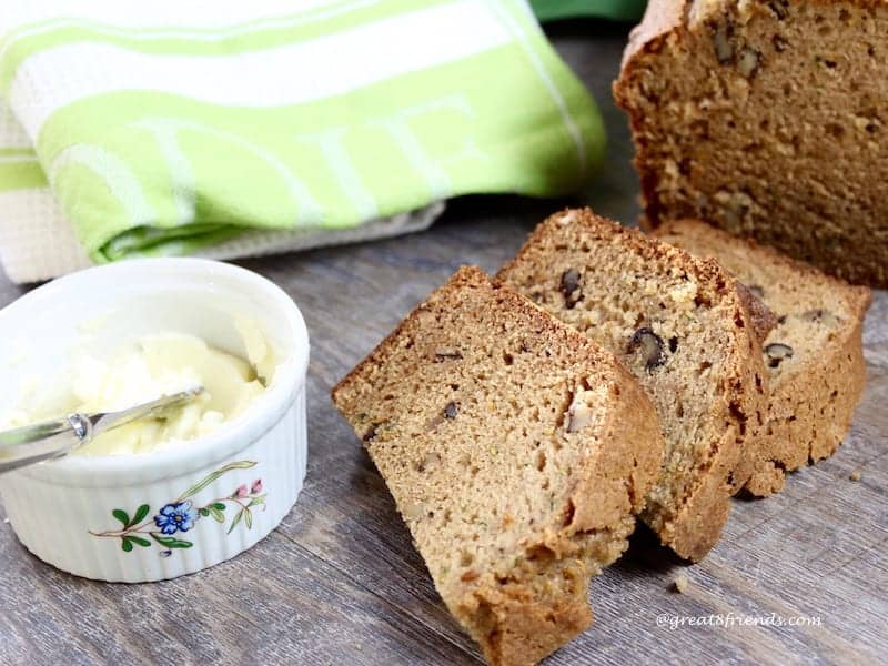 Three slices of zucchini bread and a bowl of butter.