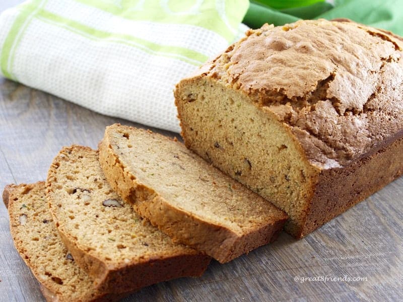 Loaf of Zucchini Bread with 3 pieces sliced and laying next to the loaf.