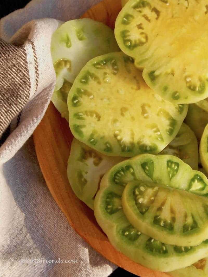 Several slices of large green tomatoes on a plate.