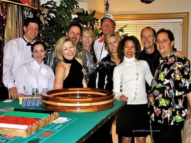 People posing for a photo in front of a roulette table.