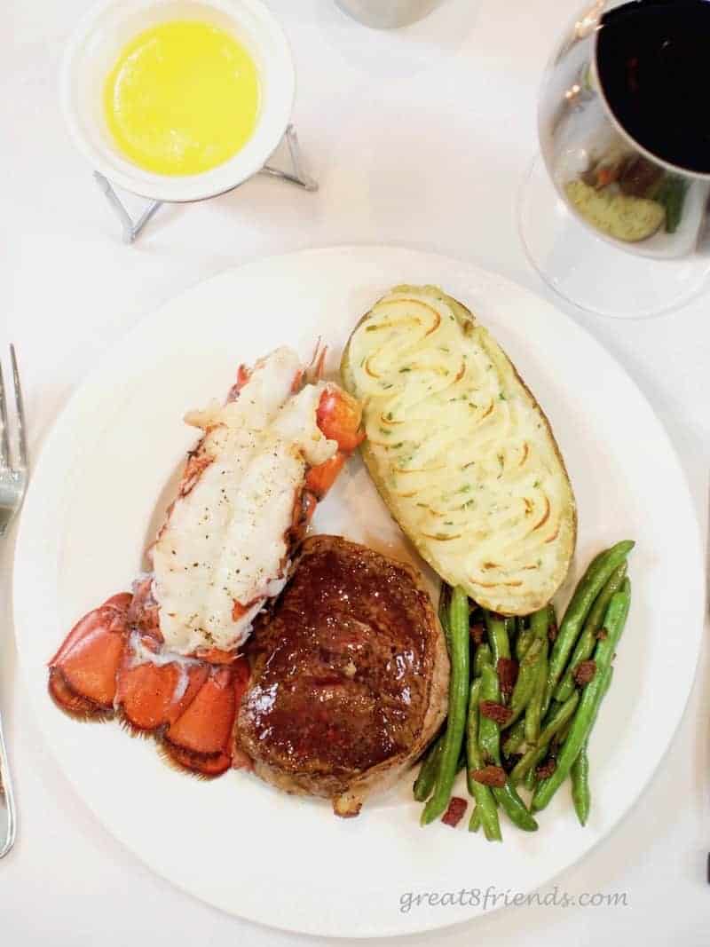 Overhead shot of dinner plate of surf and turf with potato and green beans.