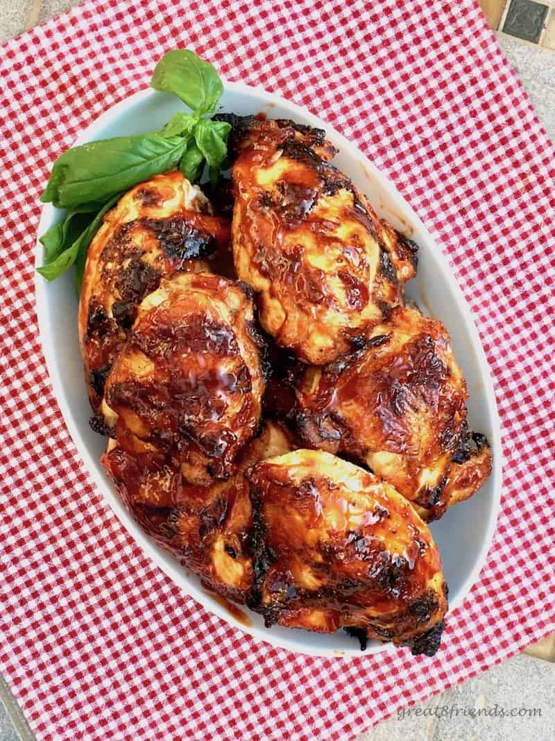 A dish of barbecued chicken on a red and white checked tablecloth.