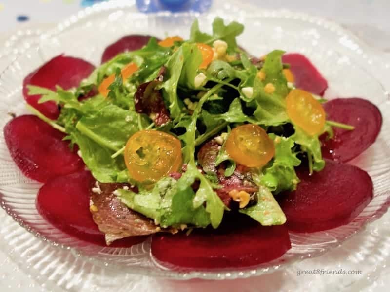 Close up of arugula salad with candied kumquats and beets.