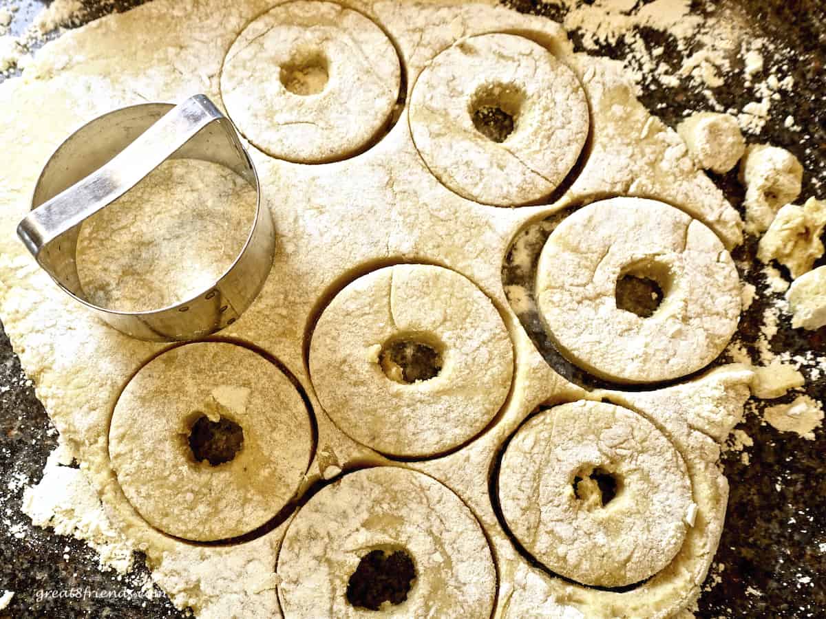 Donut dough being cut with a round cutter.