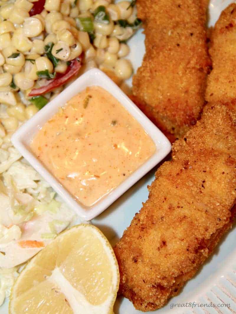 Spicy classic pan fried catfish pieces served as an appetizer with a spicy tarter sauce and corn salad on the side.