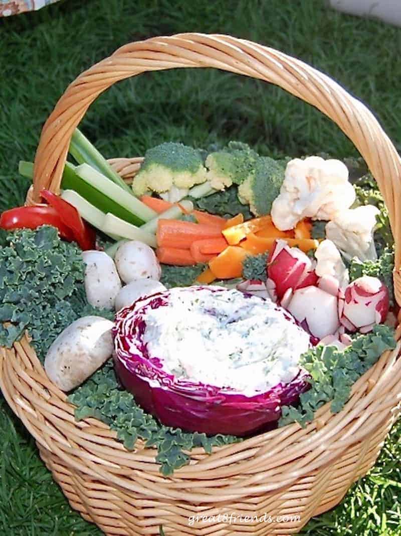 Basket of fresh cut vegetables with a dip in a carved out red cabbage.