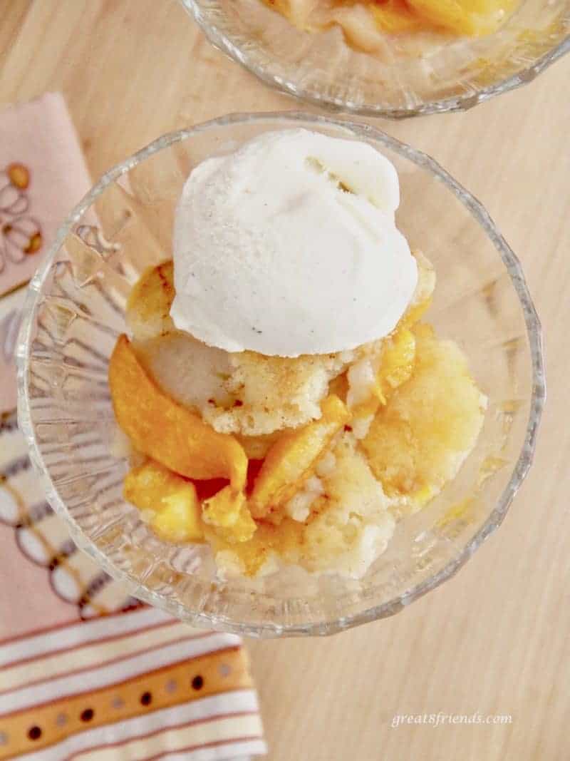 Overhead view of one serving of easy peach cobbler recipe with one scoop of vanilla ice cream on top.