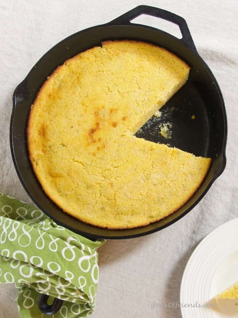 Overhead shot of cornbread in a skillet with one slice missing.