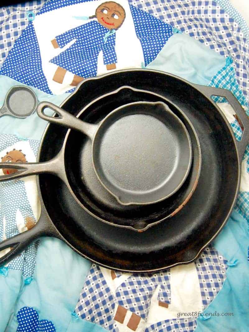 Overhead shot of three cast iron skillets stacked on a quilt.
