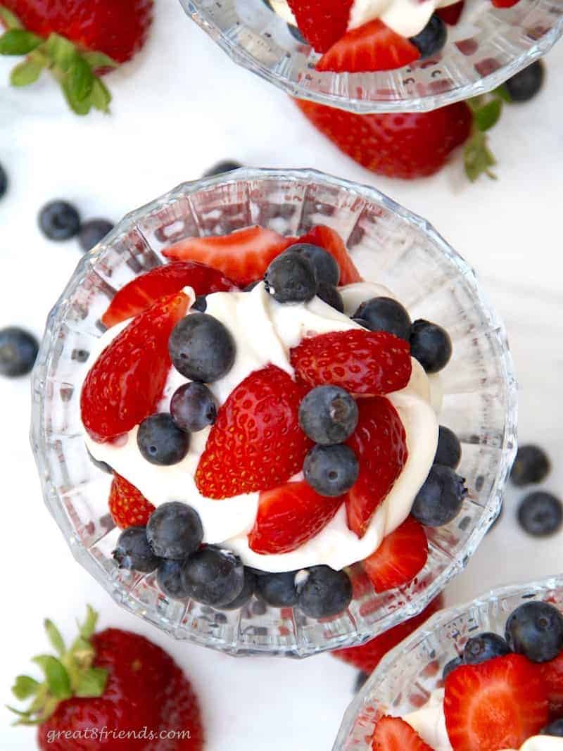 Overhead view of cheesecake mousse served with cut strawberries and blueberries.